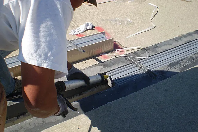 Angelus Waterproofing employee adds caulking to an expansion joint of Montclair Plaza parking structure
